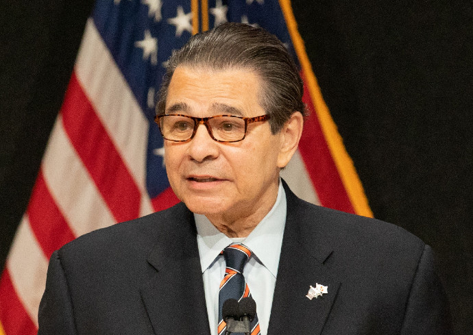 person speaking in front of American flag