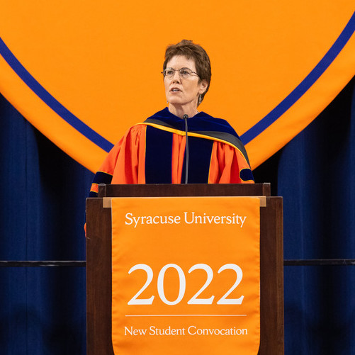 person in academic regalia standing at podium