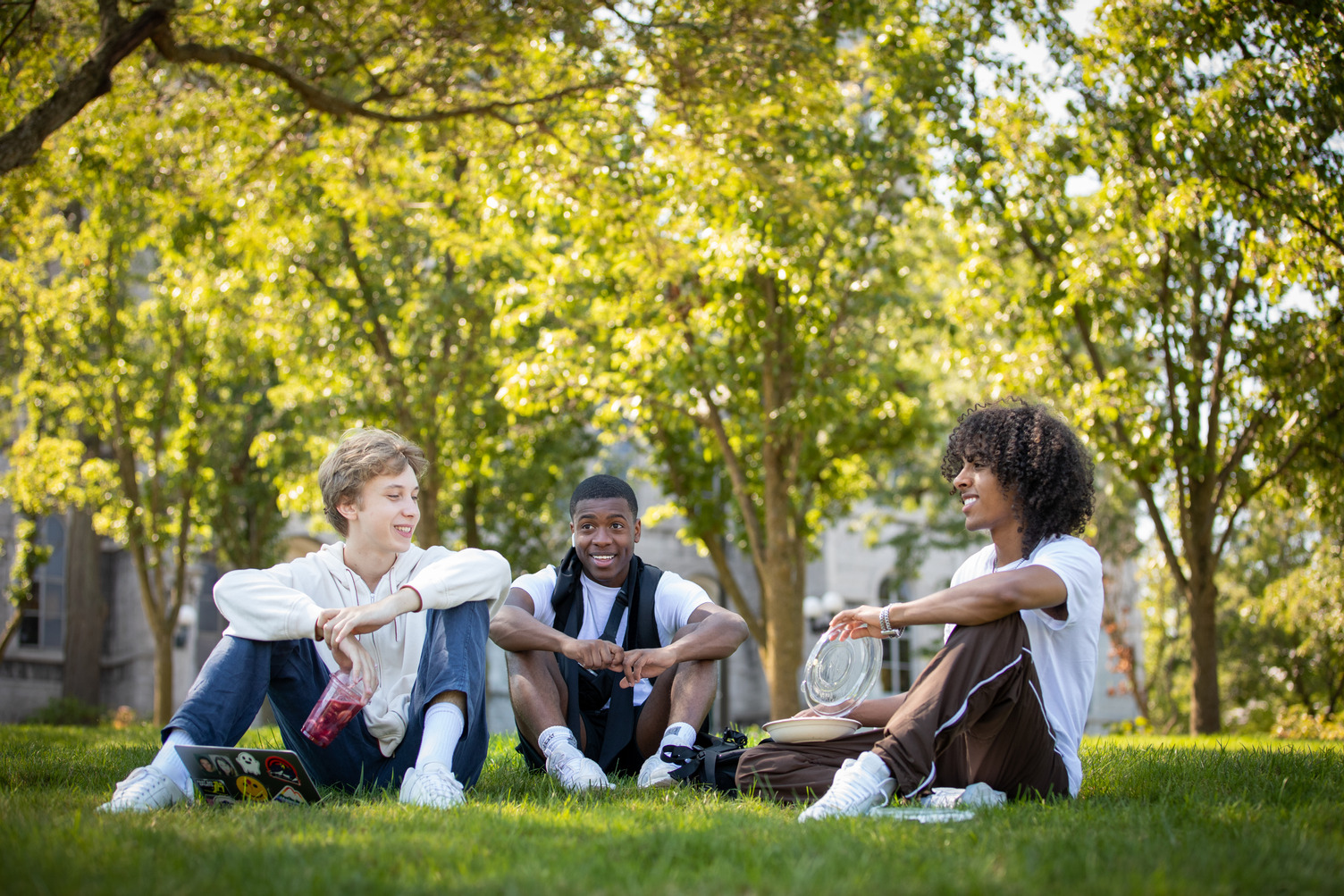 three students sit together on the Quad on the first day of classes Fall 2022 semester