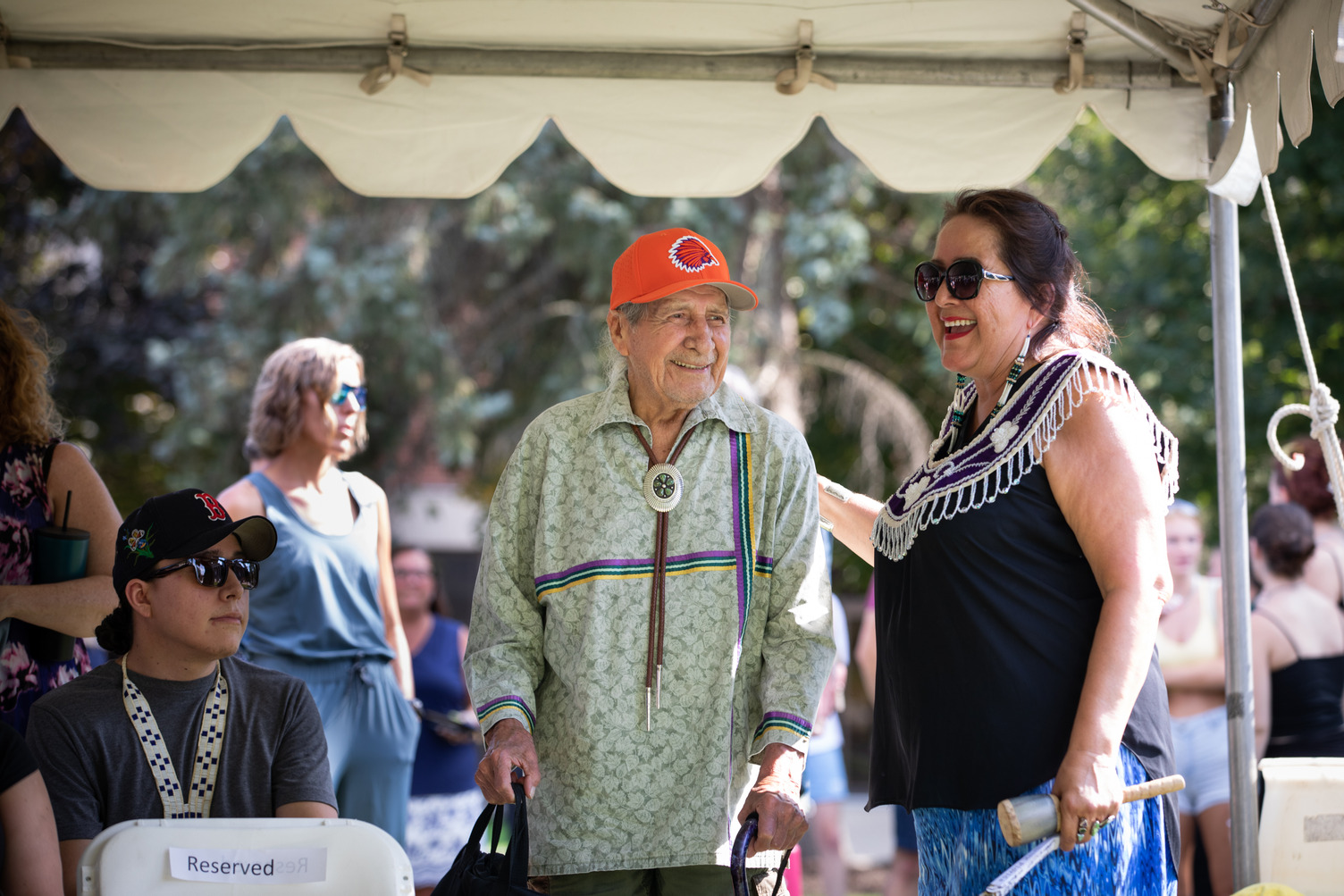 People gather beneath a tent at the 2022 Haudenosaunee Welcome Gathering