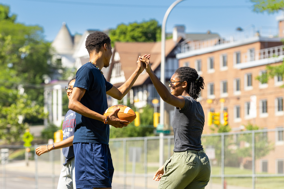 Two students high-fiving each other during a football game.