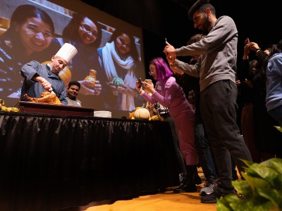 People taking pictures of chef carving turkey