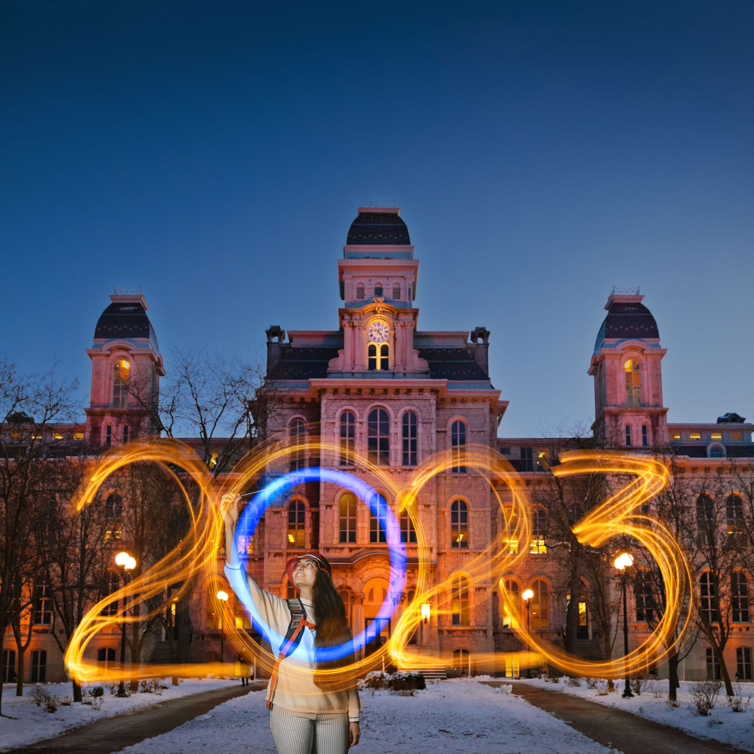 Individual standing in front of campus building using sparklers to write 2023