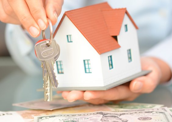A miniature house with a set of keys and a pile of money below.