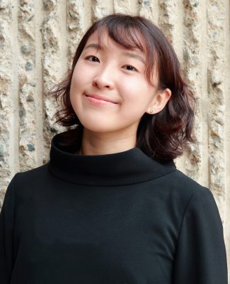 Woman smiling in front of stone wall.