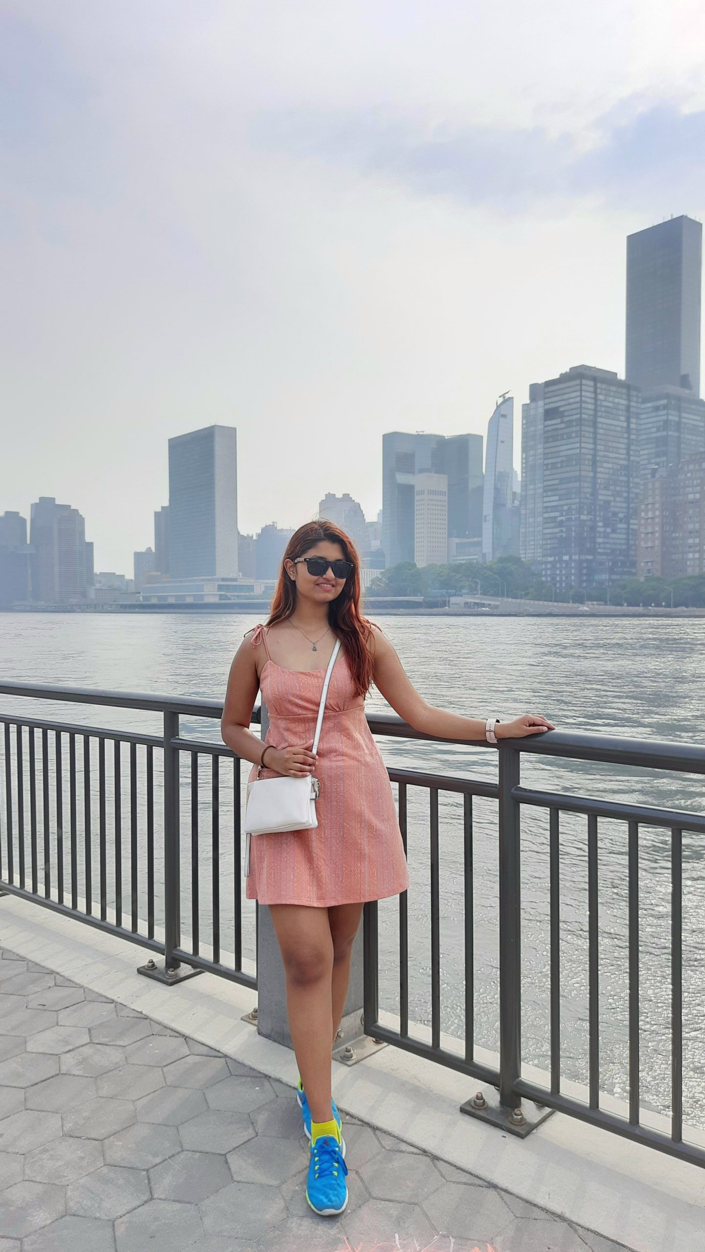 Individual standing along the water with the New York City skyline in the background.