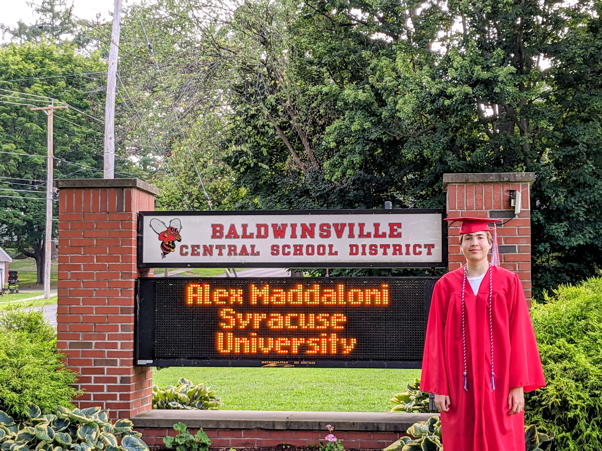 High school graduate in front of sign