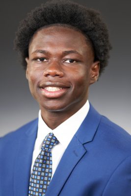 A man smiles while posing for a headshot indoors.
