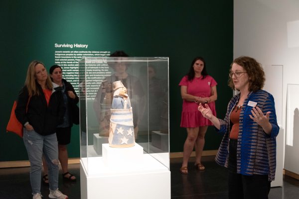 Individual speaking to a group while standing in front of an art display.