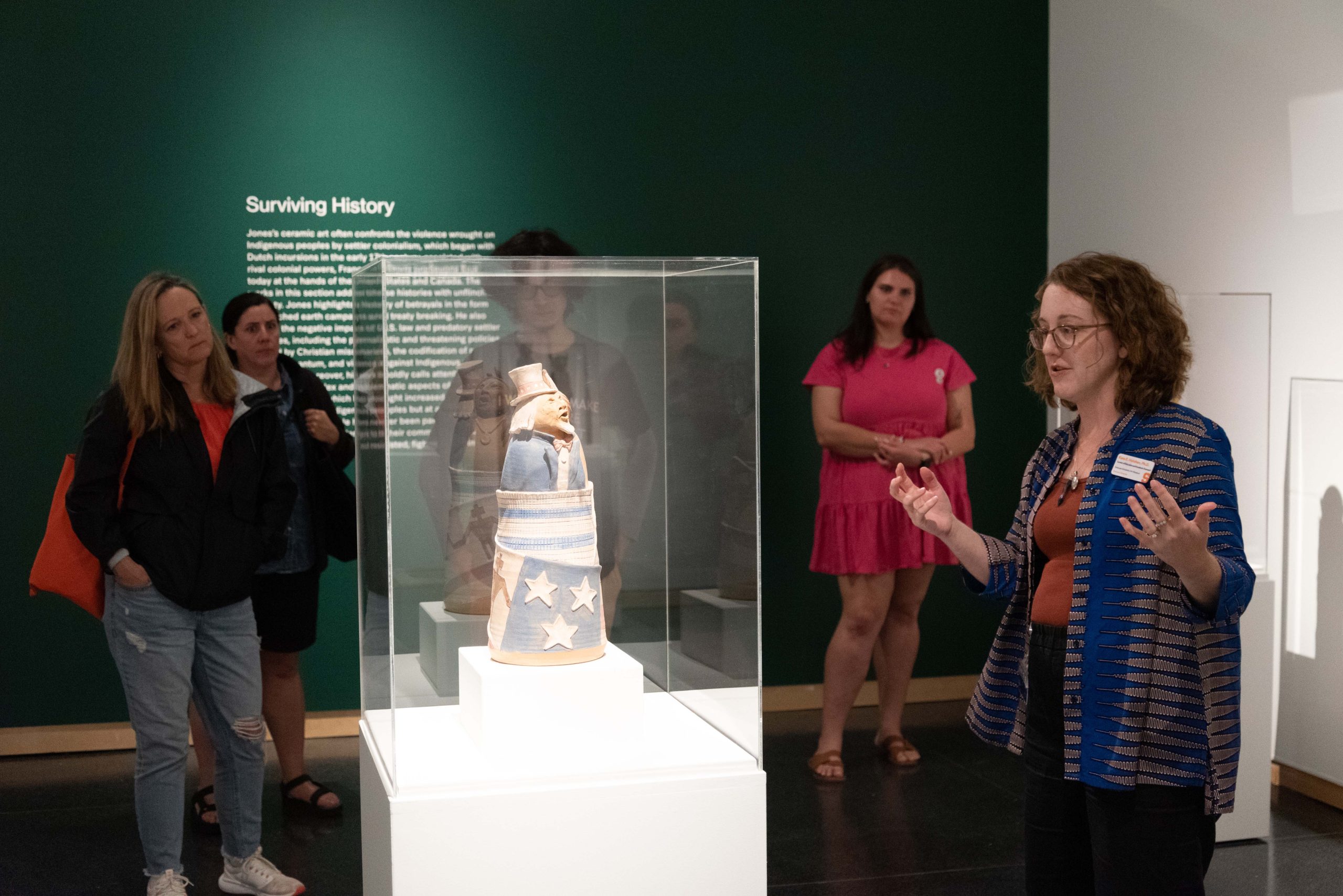 Individual speaking to a group while standing in front of an art display.