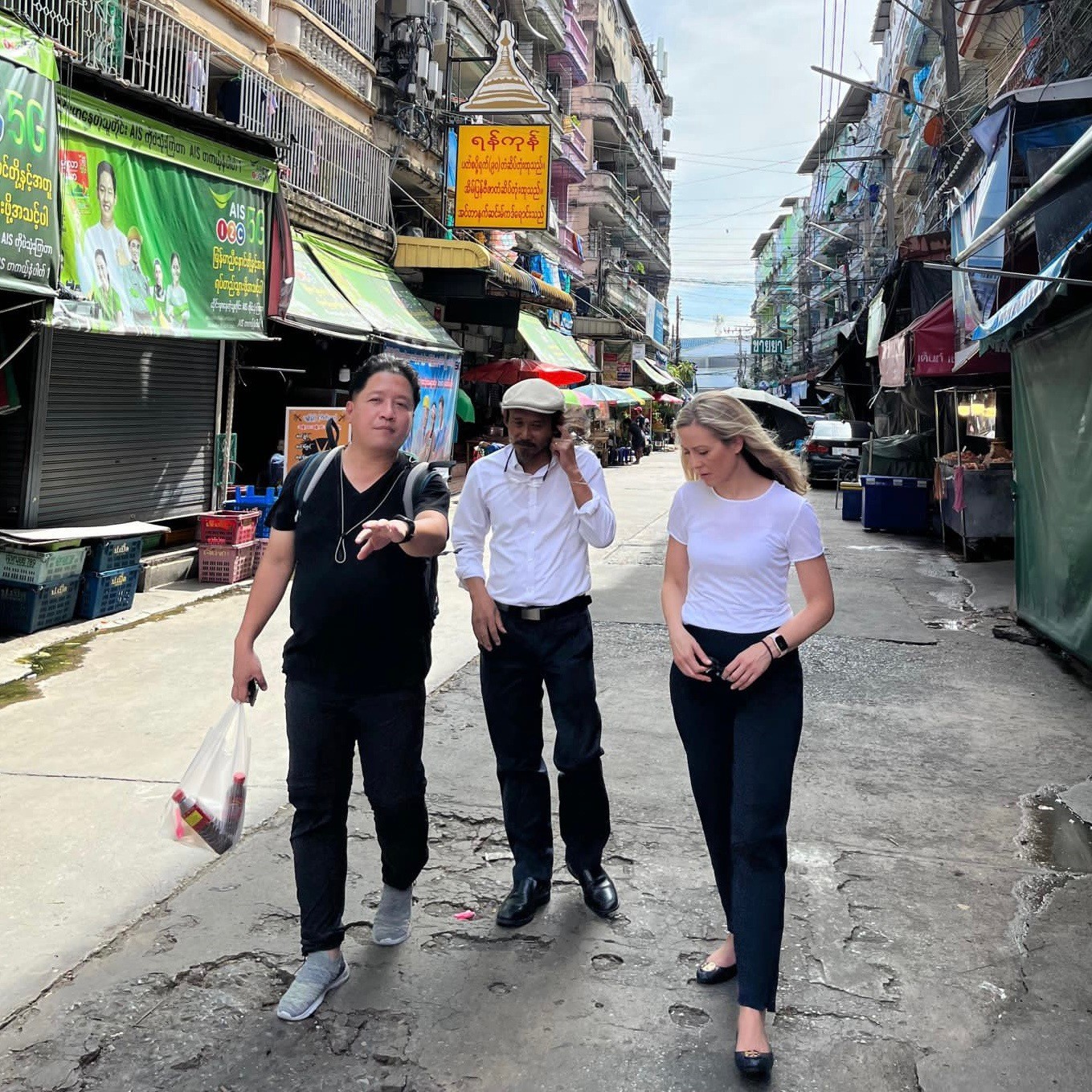 three people walking down a store-lined street