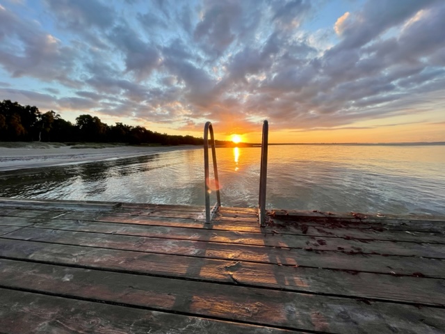 Sunrise on a dock over water.