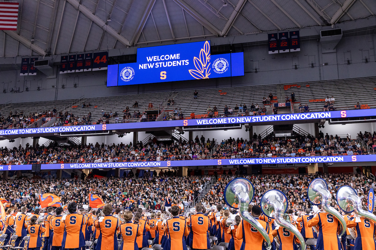 Shot from behind the marching band showing a crowd of students in the stands during New Student Convocation