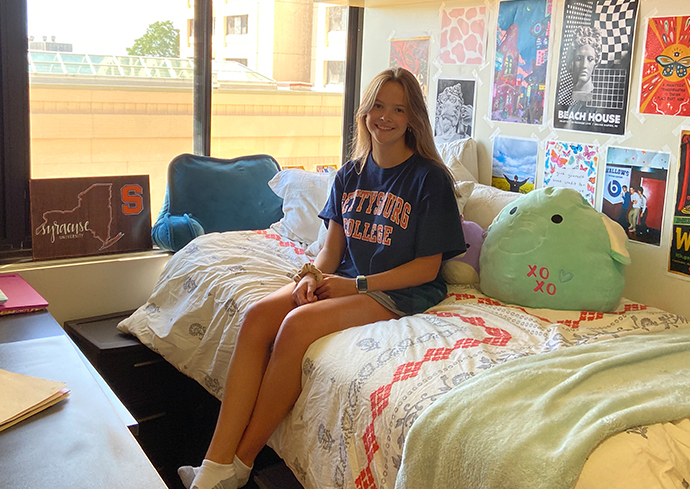 Individual sitting on a bed in a residence hall