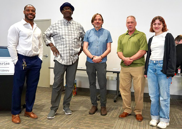 Group of people standing together in the front of a room.