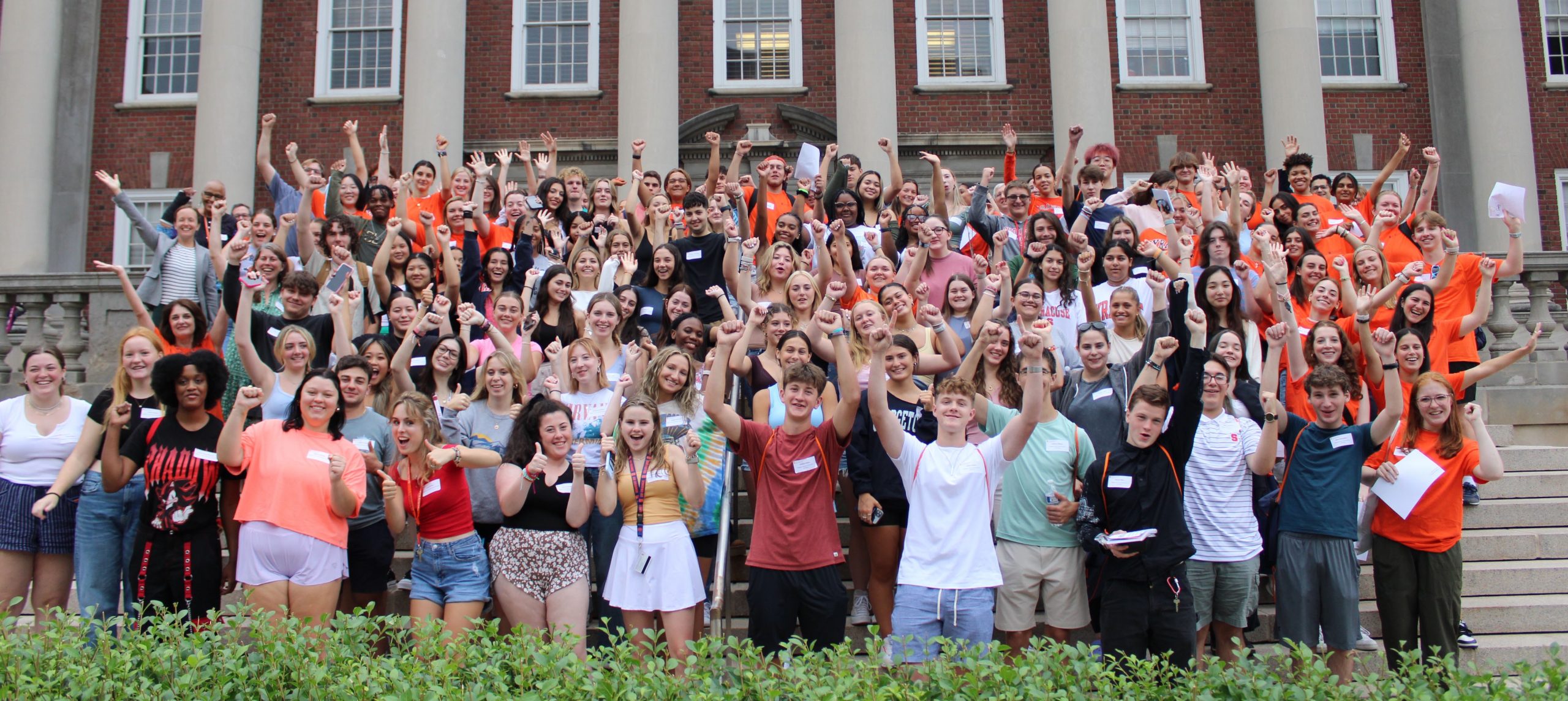 Large group of students all gathered together with their arms raised cheering