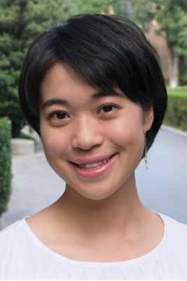 A woman smiles while posing for a photo outdoors.