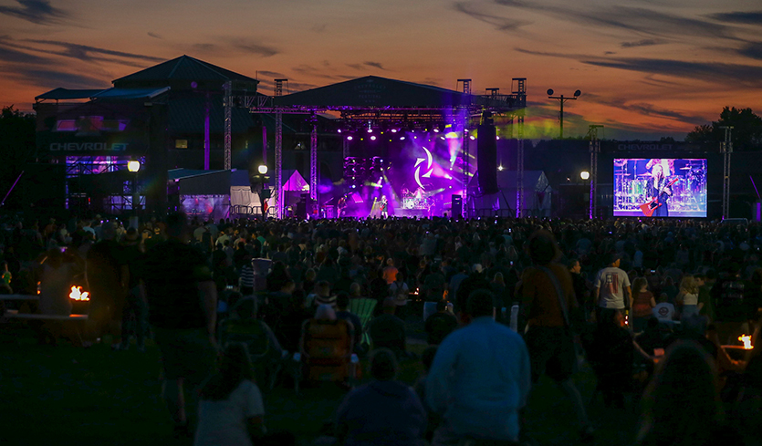 Band on stage during a performance for a large crowd.