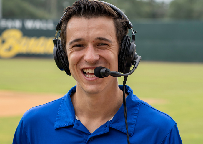 A man wearing a blue polo calls a baseball game for the Savannah Bananas.