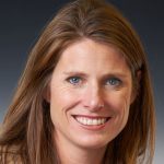 A woman smiles while posing for a headshot indoors.