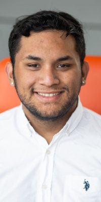 A man smiles for a photo while wearing a white dress shirt.