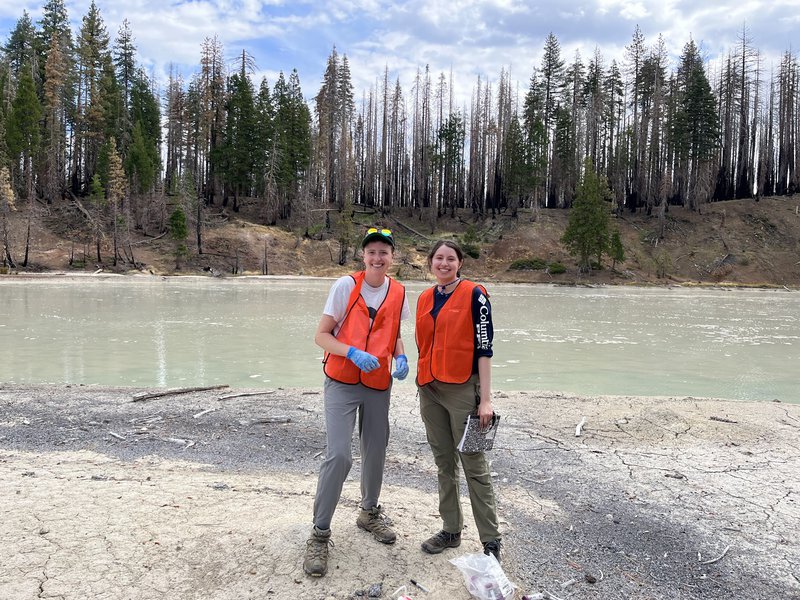 two people standing at edge of lake
