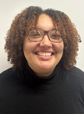 A woman smiles for a headshot while wearing a black sweater.