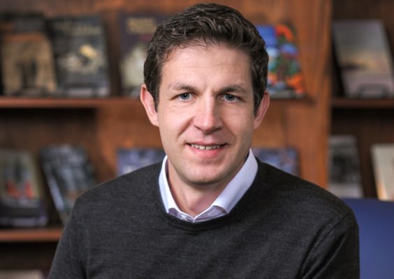 A man smiles while posing for a photo indoors.
