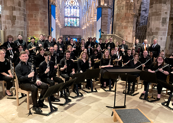 The Wind Ensemble sitting together for a performance in a church