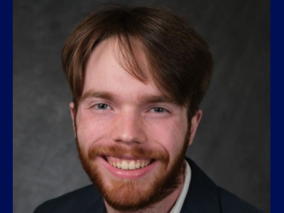 A man smiles while posing for a headshot indoors.