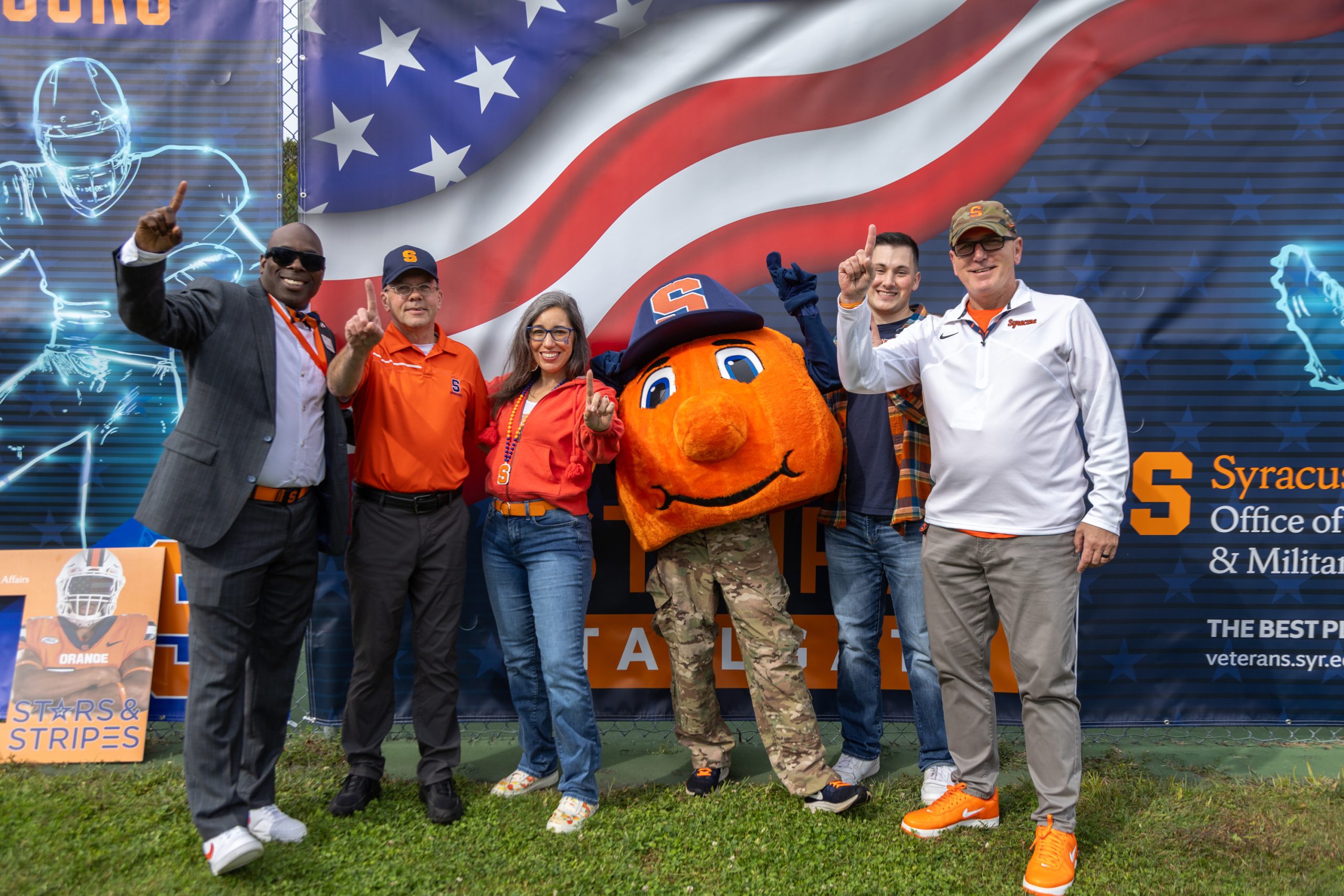 Several individuals standing with Otto making the number one sign with their fingers