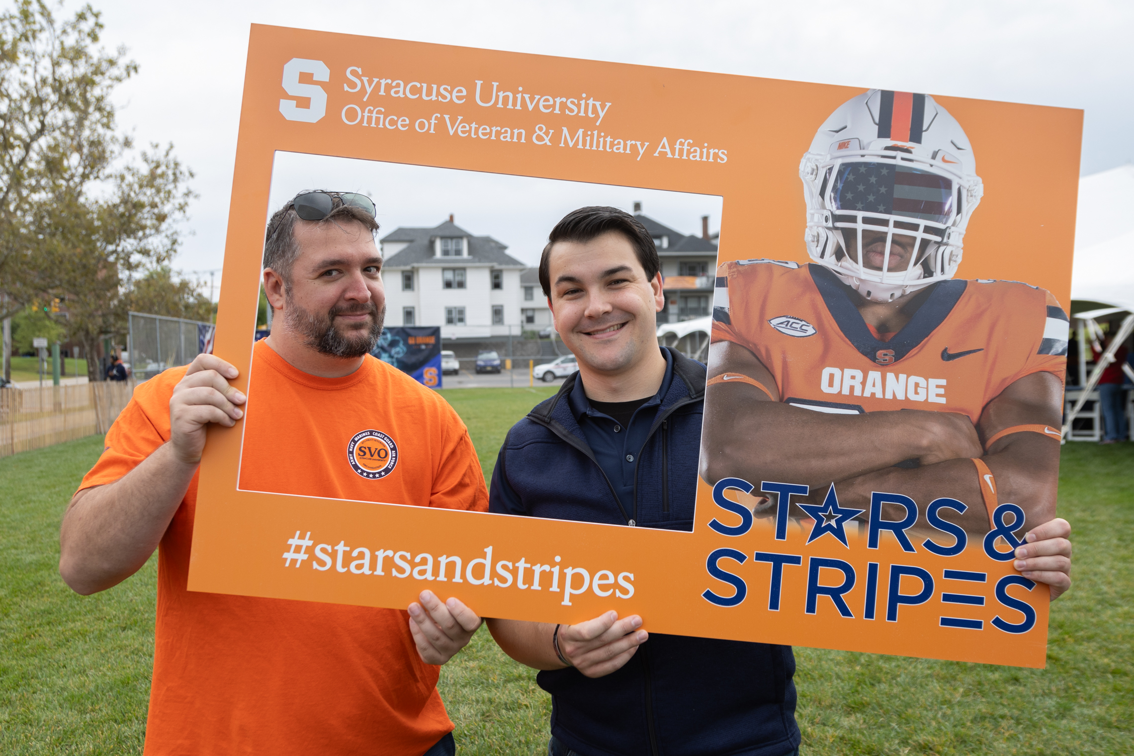 Two individuals holding up a sign with a football player on it.