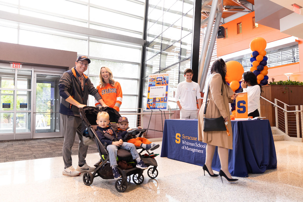 two people pushing stroller with two children in front of booth with group of people