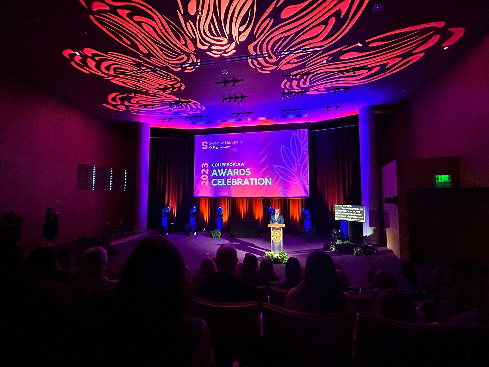 person standing on stage in front of screen that states 2023 College of Law Awards