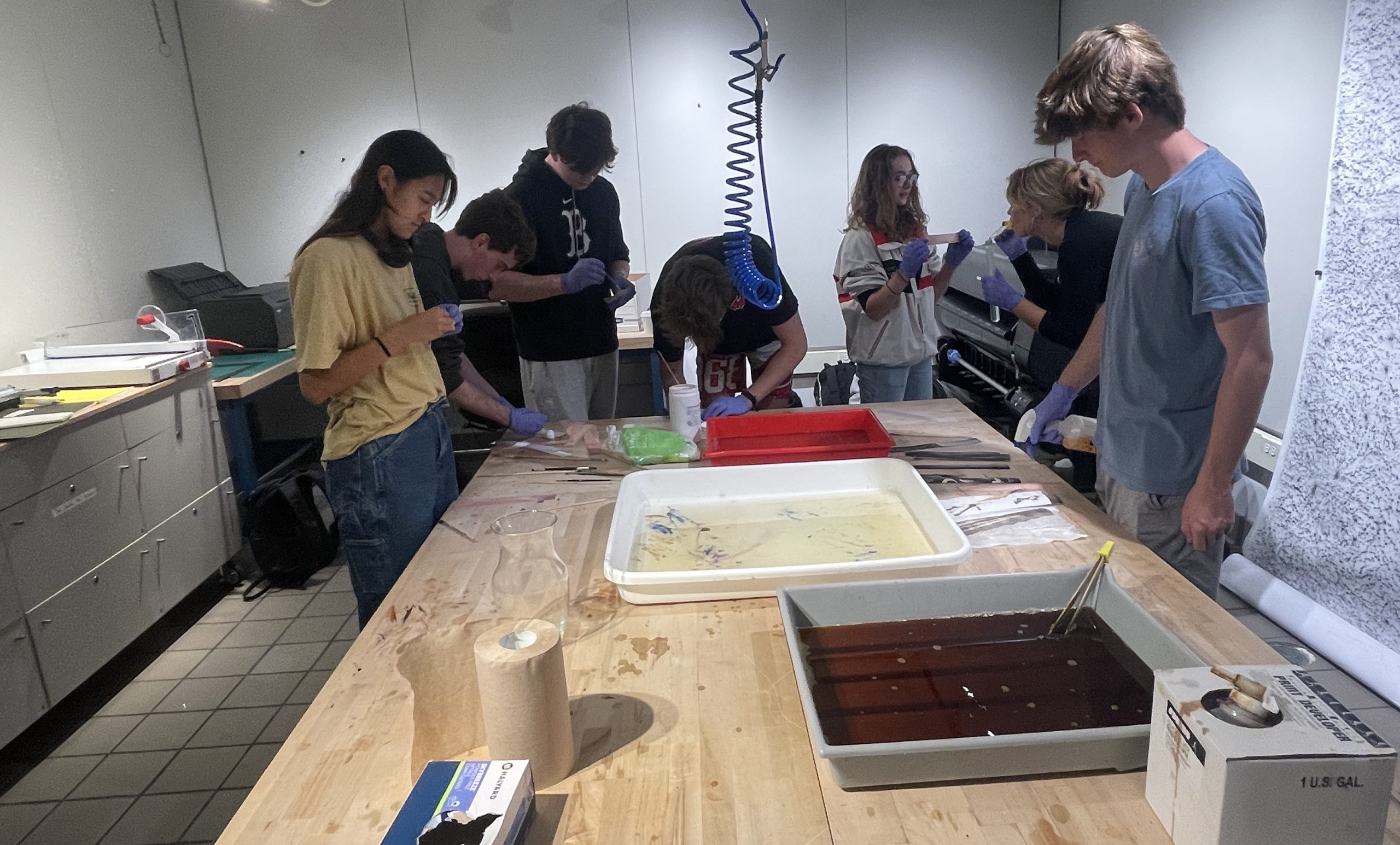 Several students working in a photography darkroom