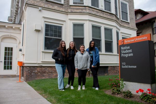 four people standing outside building