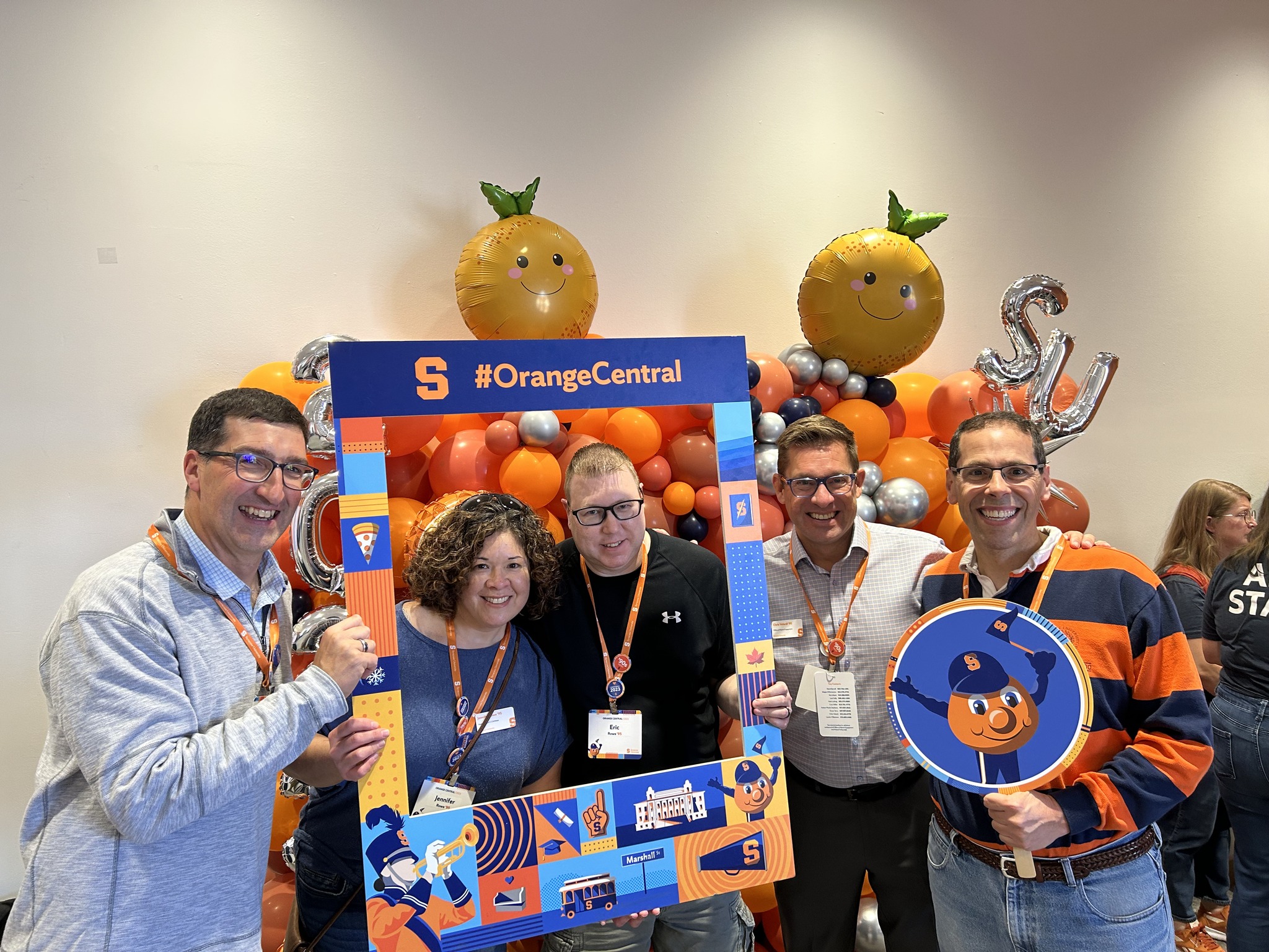 five people posing with decorative frame in front of ballon display