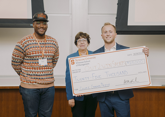 three people standing holding large check