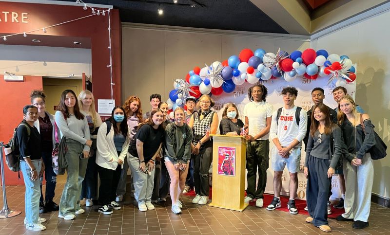 a large group of studente posts in front of display at Syracuse Stage