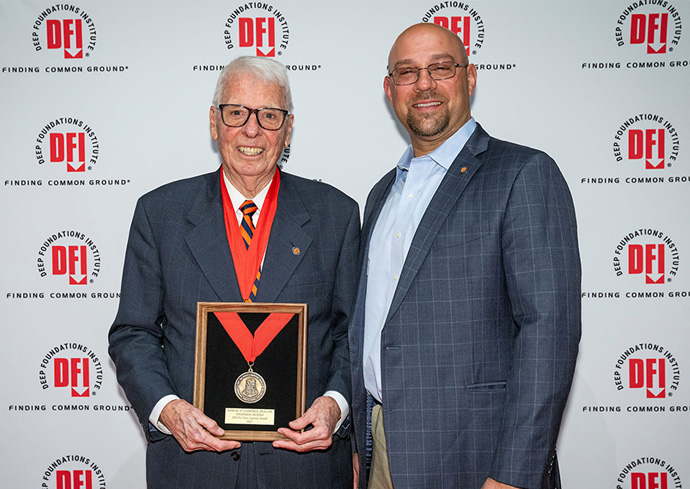 Sam Clemence and ECS alum Matthew Conte ’06 pose together at an awards ceremony in front of a Deep Foundations Institute step-and-repeat banner