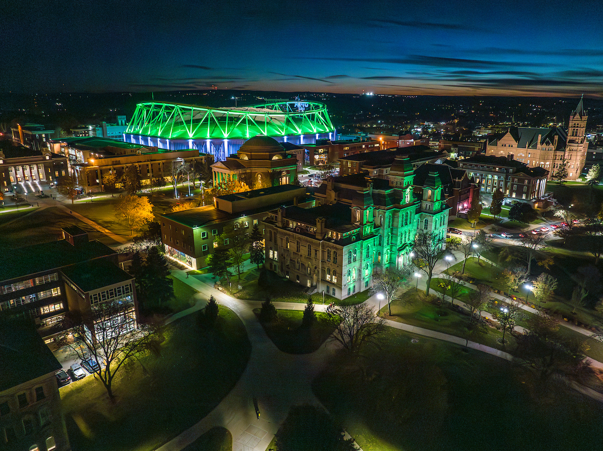 A drone captures buildings across campus lit up with green lights in honor of Veterans Day.