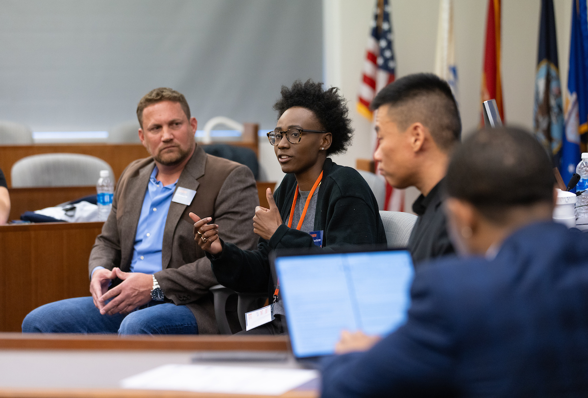 Panelists speaking at the front of the room with students sitting in the audience