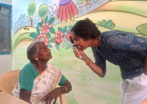 A woman administers an eye exam on another woman.