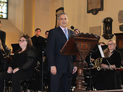 Milton Laufer offers welcoming remarks at Wind Ensemble performance in London