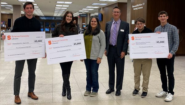 group of individuals standing in Bird Library holding up oversized checks