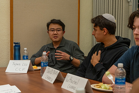 Individual sitting at a table with others speaking.