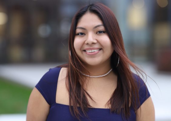 A woman smiles for a headshot while standing outside.