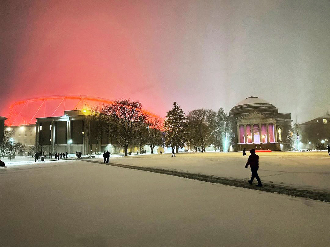 people traverse the Syracuse University Quad with a light dusting of snow