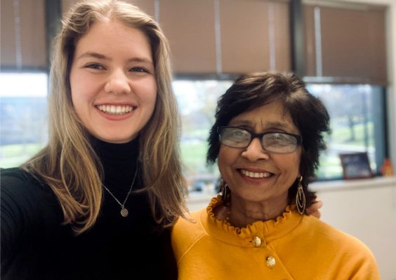 A student and a faculty member smile while posing for a photo.