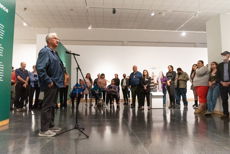 Person speaking into a microphone to a room full of people.